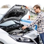Auto defects: young man checking inside the hood of his car