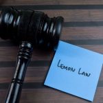 Concept of Lemon Law write on sticky notes with gavel isolated on Wooden Table.