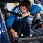 Male mechanic examining car seat belt in garage